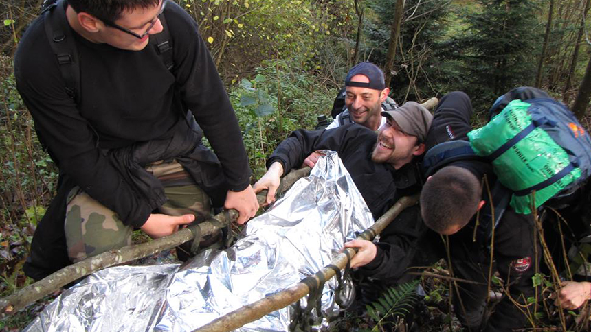 l'équipe porte un blessé sur un brancard en branches